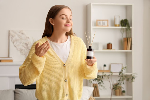 A woman with a reed diffuser at home.