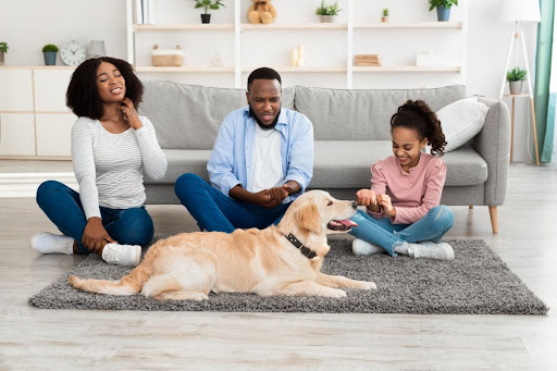 A family with itchy skin sitting on the floor with a dog.